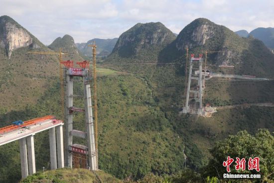 11月22日，正在建設(shè)中的峰林特大橋。當(dāng)日，隨著1470噸裝配化預(yù)制中橫梁提升到位，貴州省黔西南布依族苗族自治州興義環(huán)城高速公路峰林特大橋4號主塔中橫梁成功吊裝，由此刷新了山區(qū)峽谷橋梁預(yù)制吊裝混凝土構(gòu)件重量世界記錄。峰林特大橋是屬全線控制性工程。大橋跨越馬嶺河峽谷，全長1163米，主跨采用550米懸索橋，橋面離谷底364.2米，是中國山區(qū)第一座大跨徑鋼混疊合梁懸索橋。中新社記者 瞿宏倫 攝